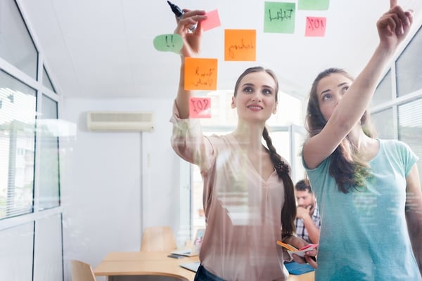 2 female office coworkers with post its-1