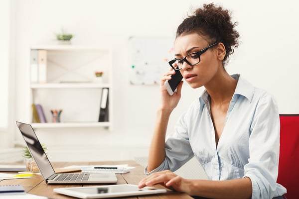 woman Negotiating on phone surrounded by laptop, tablet, and phone