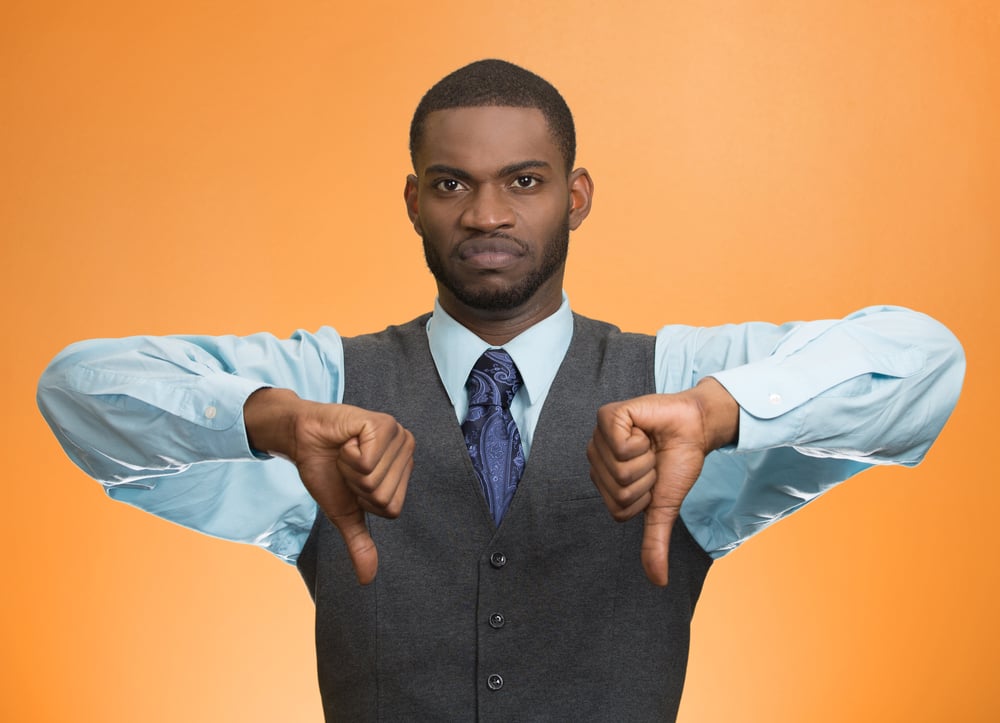 Closeup portrait unhappy, angry, mad, annoyed, grumpy man giving thumbs down gesture, looking with negative facial expression disapproval isolated orange background. Human emotion hand sign, attitude