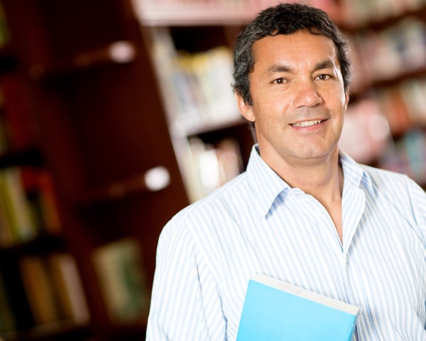 Old male university student smiling at the library