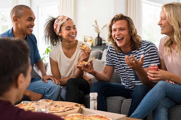 Small group of younger people eating pizza and having fun
