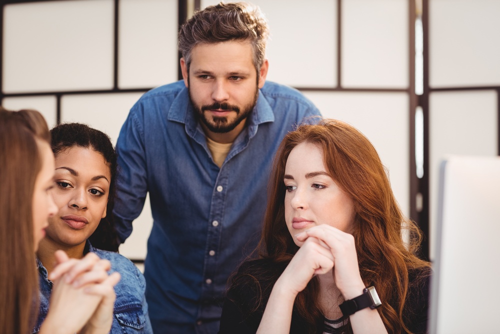 Business people looking at female coworkers in creative office