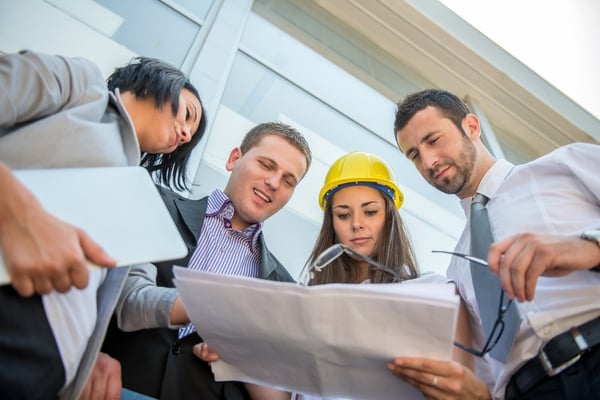 Business people reviewing construction plans in front of building