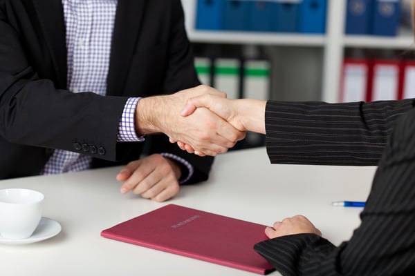 Businessman and businesswoman shaking hands at office desk