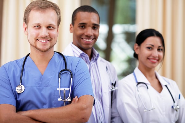 Doctor in blue scrubs with his colleagues behind