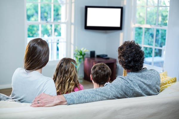 Family watching television while sitting on sofa at home