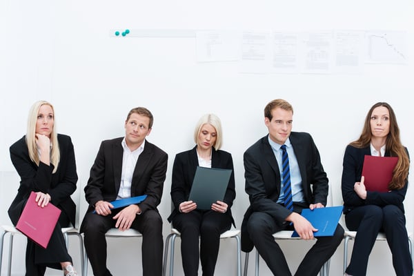 A group of stressed applicants waiting for interviews sitting in chairs