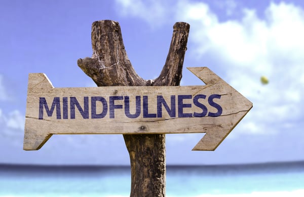 Mindfulness wooden sign with a beach on background