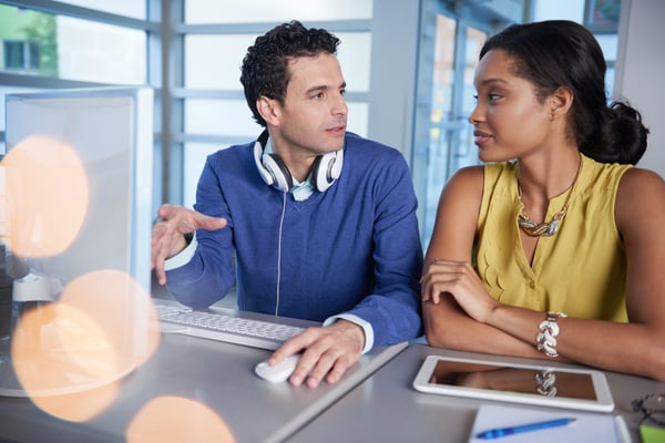 Two  colleages discussing ideas using a tablet and computer-1